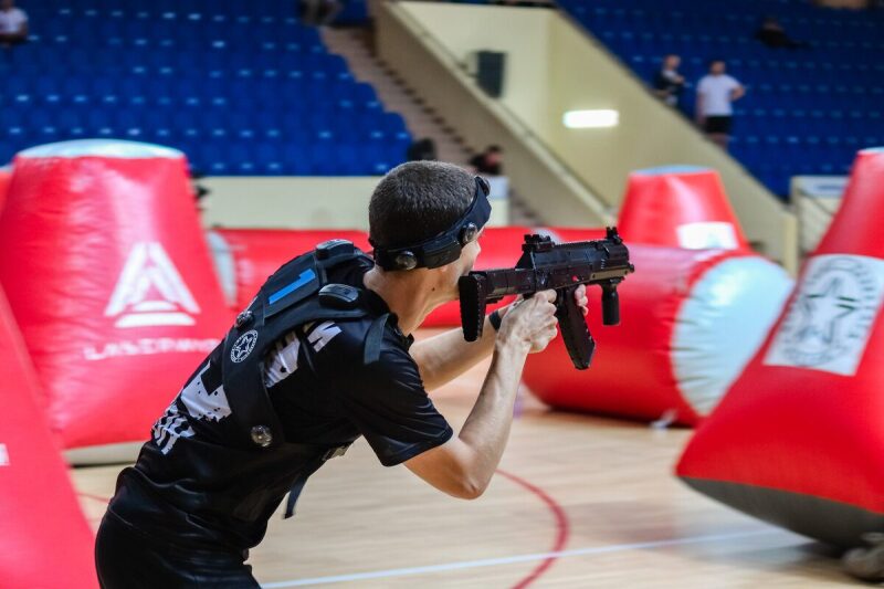 Игрок LASERWAR занимает позицию у красного надувного укрытия.